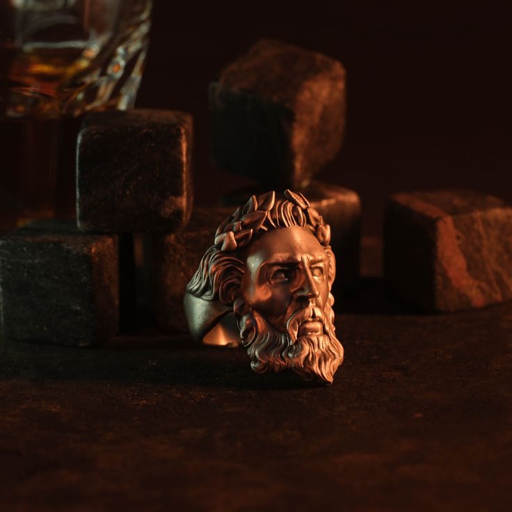 a bronze busturine is sitting next to some rocks and a glass on the table