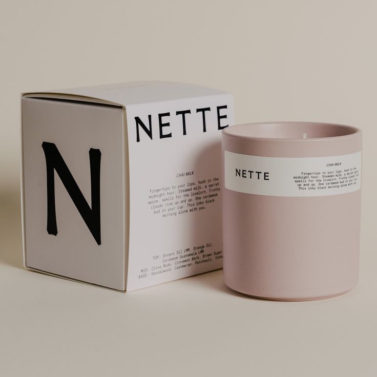 a pink candle sitting next to a box with the letter n in black on it