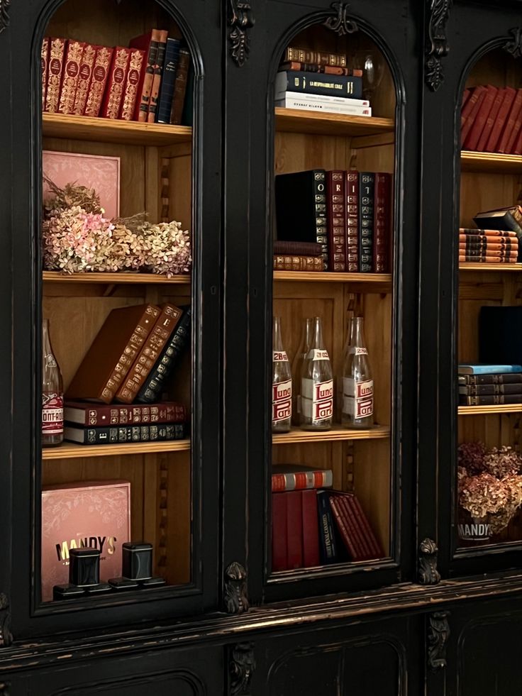 an old bookcase with many books and drinks on it's glass front doors