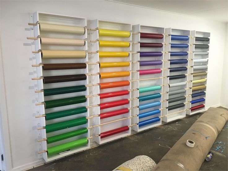 a room filled with lots of different colored rolls of paper next to a large wall