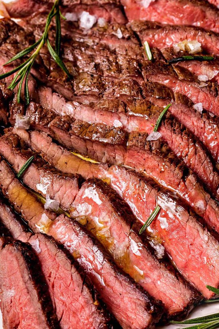 sliced steak on a plate with rosemary garnish