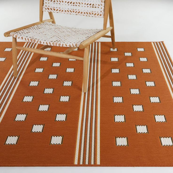 a chair sitting on top of an orange and white rug next to a wooden chair