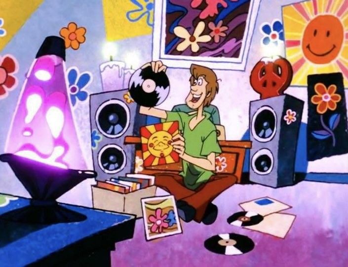 a man sitting on top of a couch in front of a tv and speakers with cartoon characters around him