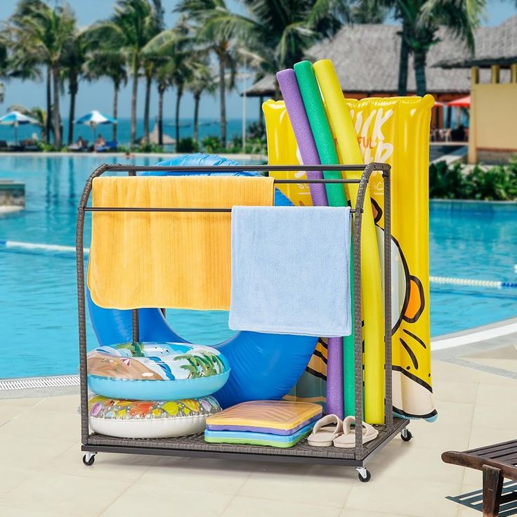 a rack that has towels and other items on it near a pool with palm trees in the background