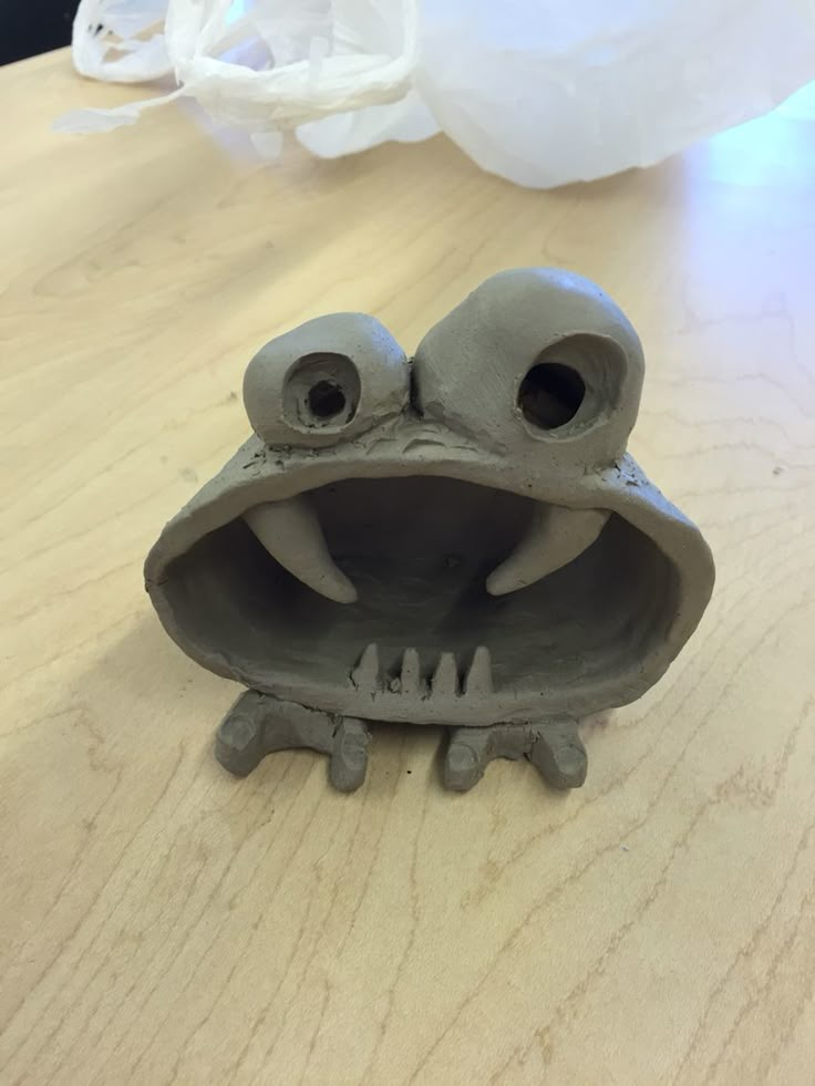 a clay frog sitting on top of a wooden table