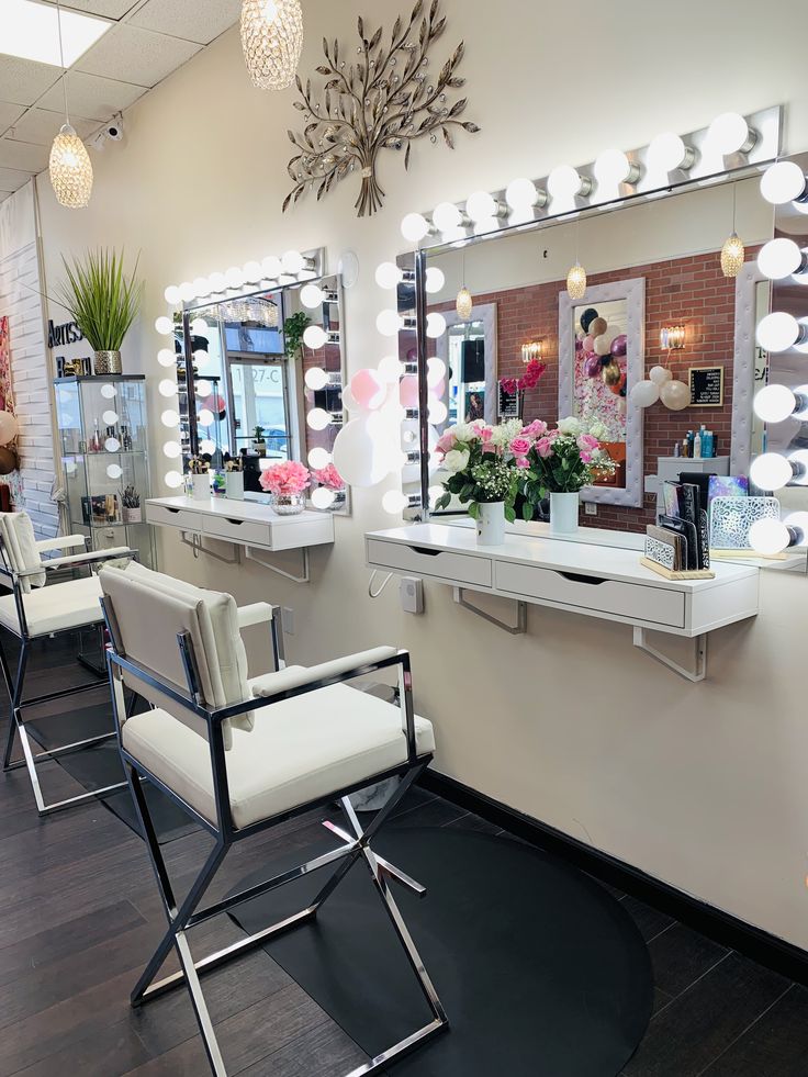 a salon with chairs, mirrors and flowers on the counter top in front of it