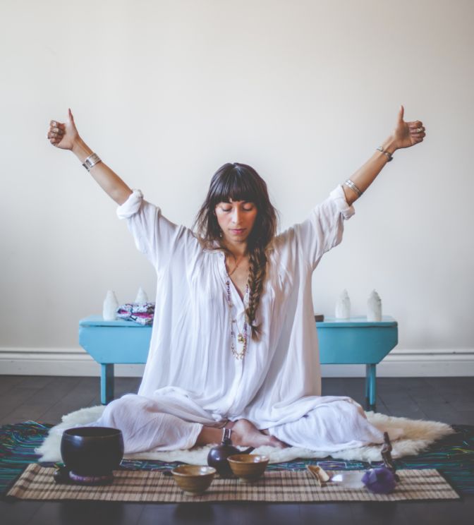 a woman is sitting on the floor with her hands in the air