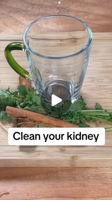 a glass cup filled with green herbs on top of a wooden cutting board next to a knife