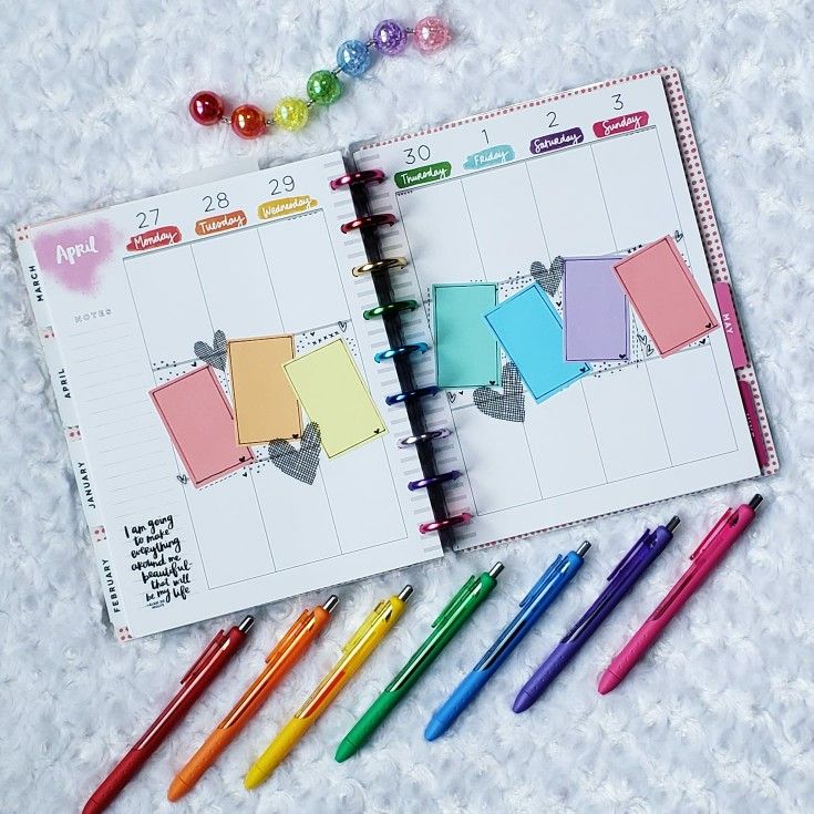 an open planner with markers, pens and candy on the side next to it are colored paper