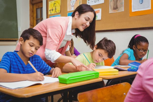 a woman is helping children with their homework in a classroom at the school desks