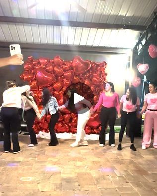 a group of people standing on top of a wooden floor in front of a giant heart