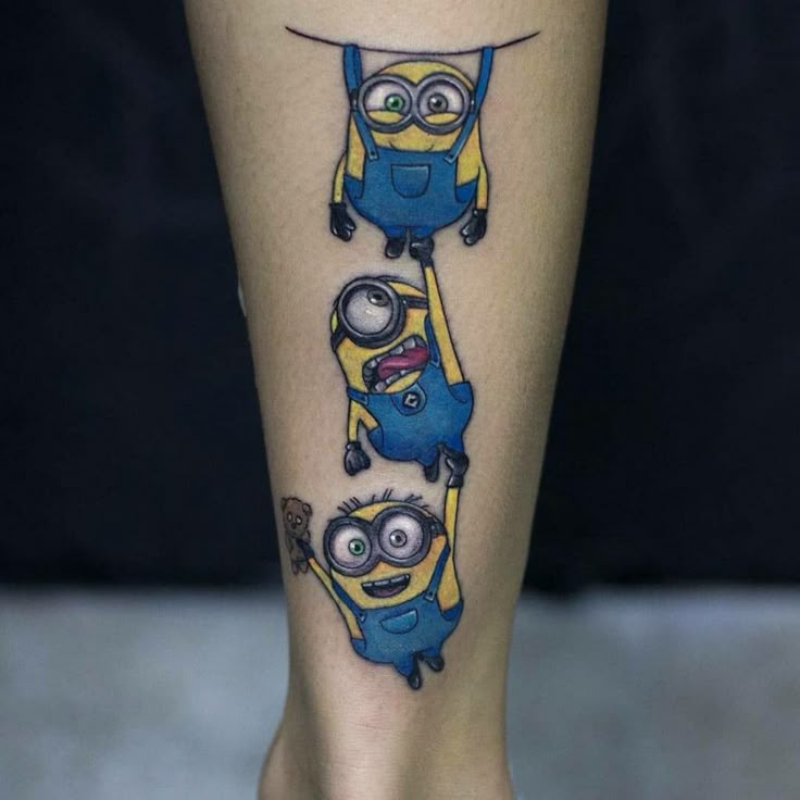 minion tattoos on the leg of a woman's legs, which are drawn in blue and yellow