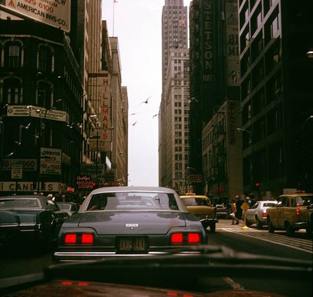 cars driving down a busy city street with tall buildings in the background royalty - free