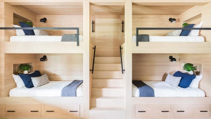 two bunk beds with blue pillows and white sheets in a room that has wood paneling