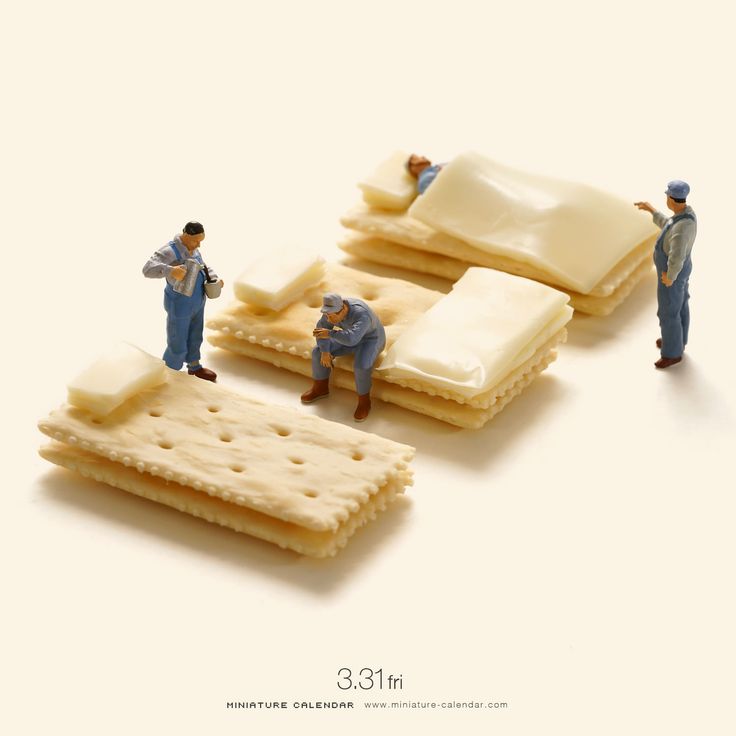 miniature figurines are laying on top of crackers and one man is standing next to them