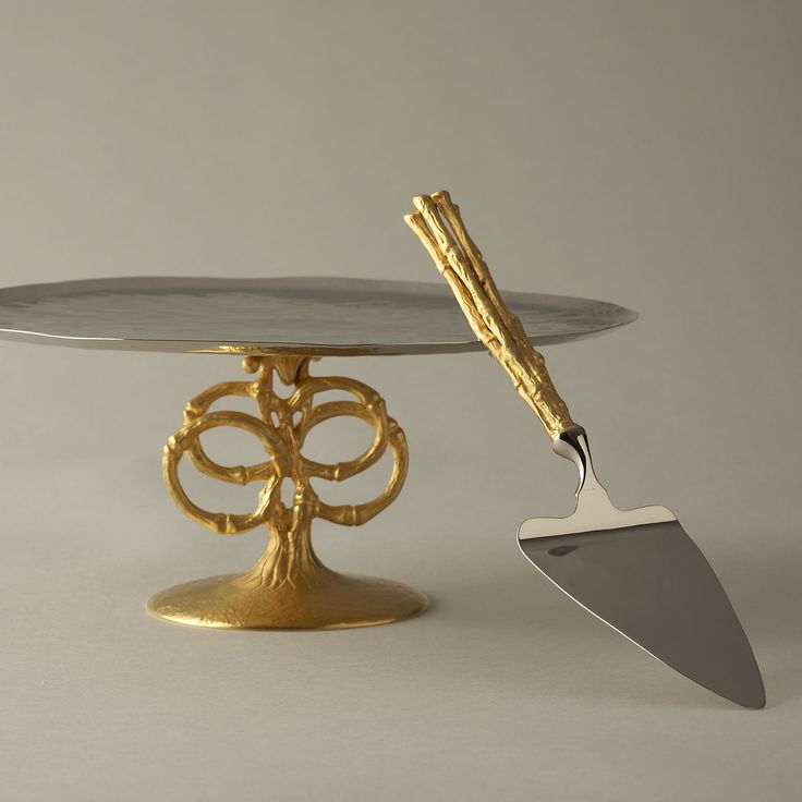 a cake stand with a gold tree on it and a metal spatula next to it