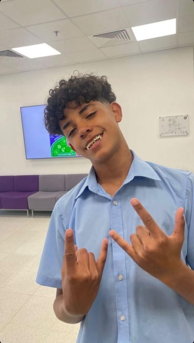 a young man making the v sign with his hands in front of him and smiling at the camera