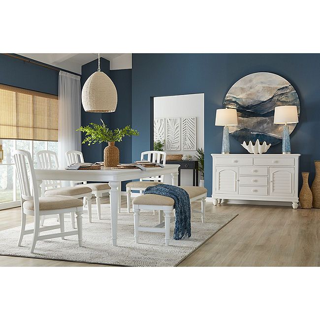 a dining room with blue walls and white furniture