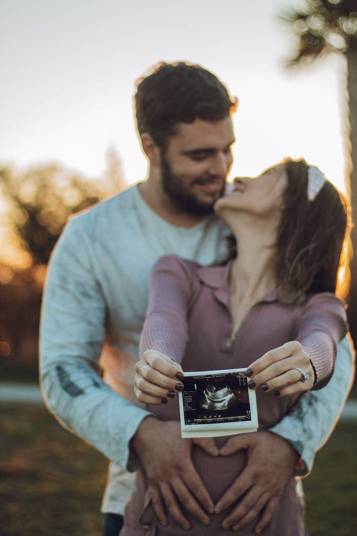 a man and woman kissing while holding a camera