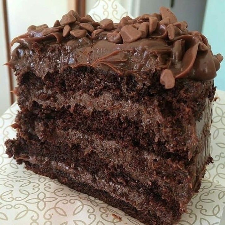 a close up of a slice of cake with chocolate frosting on a paper towel