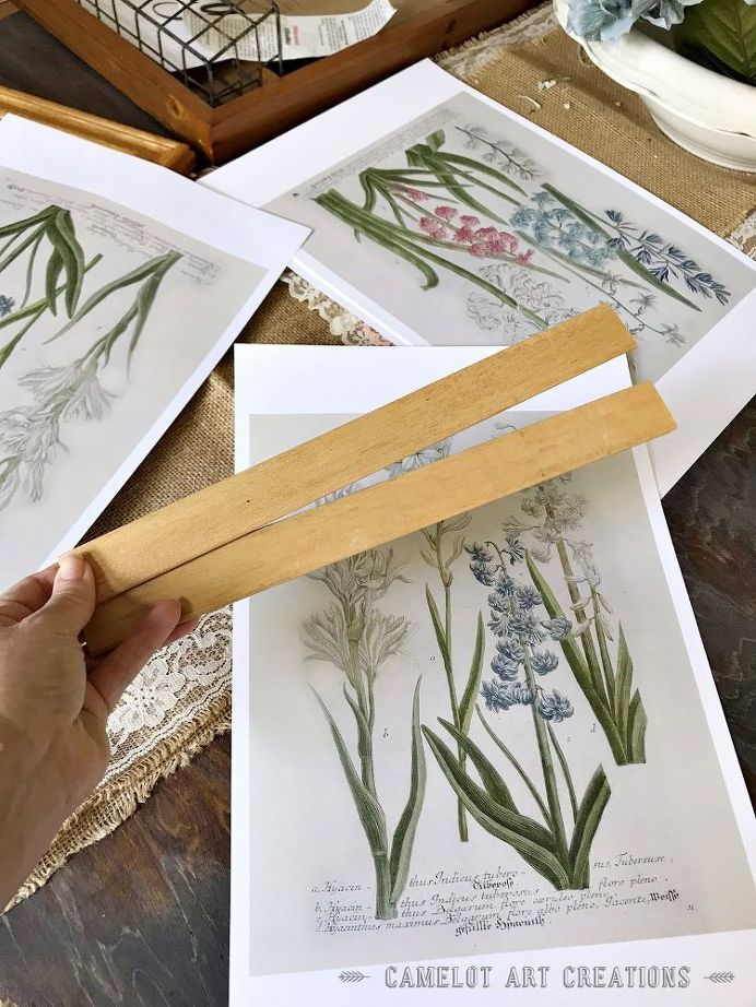 a person holding a piece of wood in front of some flowers on white paper and pictures