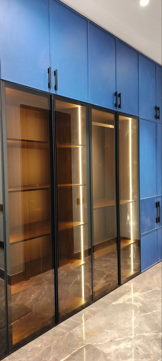 an empty room with glass doors and blue cabinets on the wall, in front of a marble floor