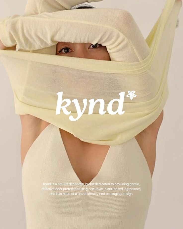 a woman is covering her face with a scarf and wearing a white top that says kynd