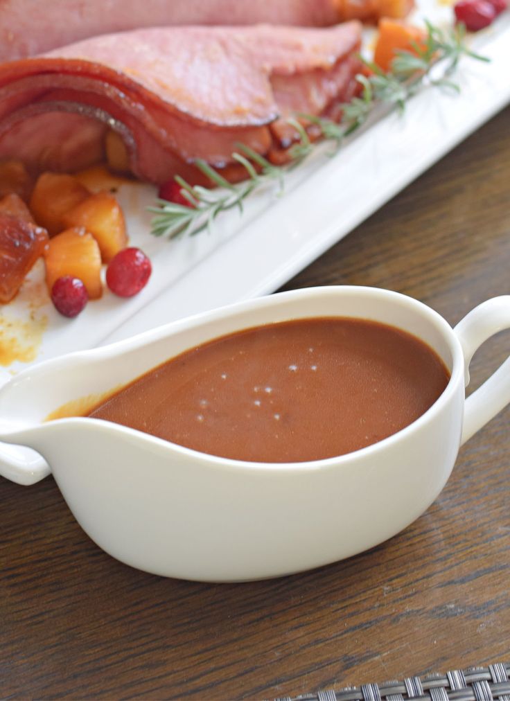 a white gravy dish with meat and fruit on the side next to it