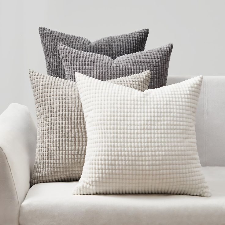 three pillows sitting on top of a white couch