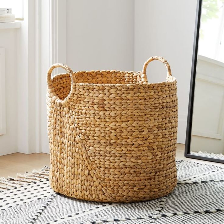 a large woven basket sitting on top of a rug next to a mirror in a room