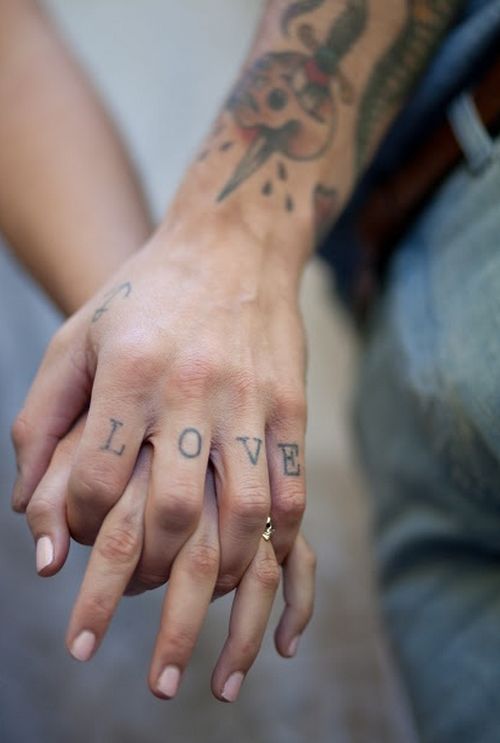 two people with tattoos on their hands holding each other's hand and one has the word love tattooed on it