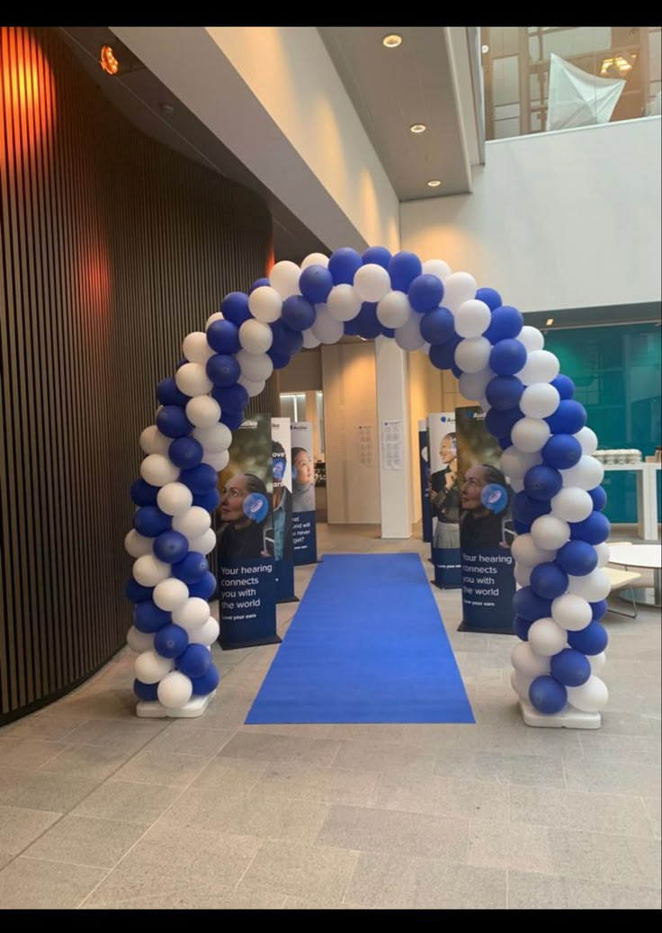 an arch made out of balloons in the middle of a hallway with blue carpeting