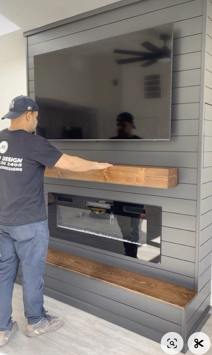 a man standing in front of a flat screen tv mounted to the side of a wall