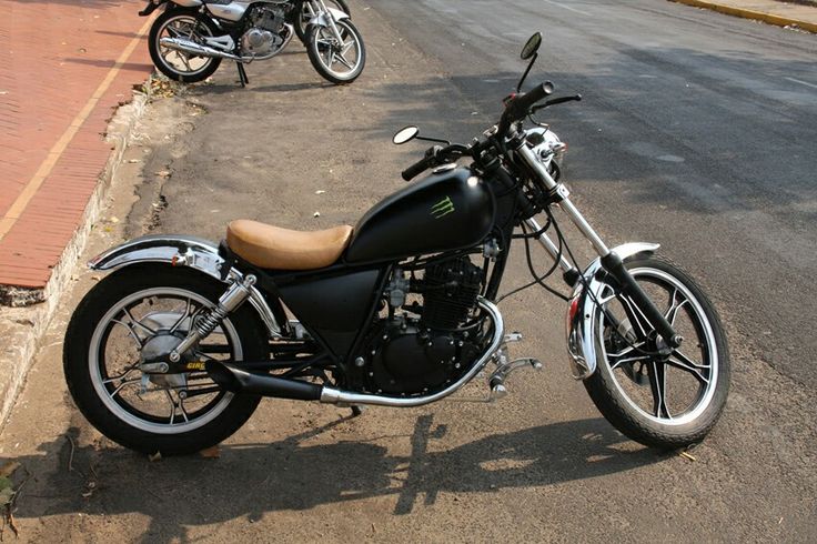 a black motorcycle parked on the side of a road next to another motorcycle in the street