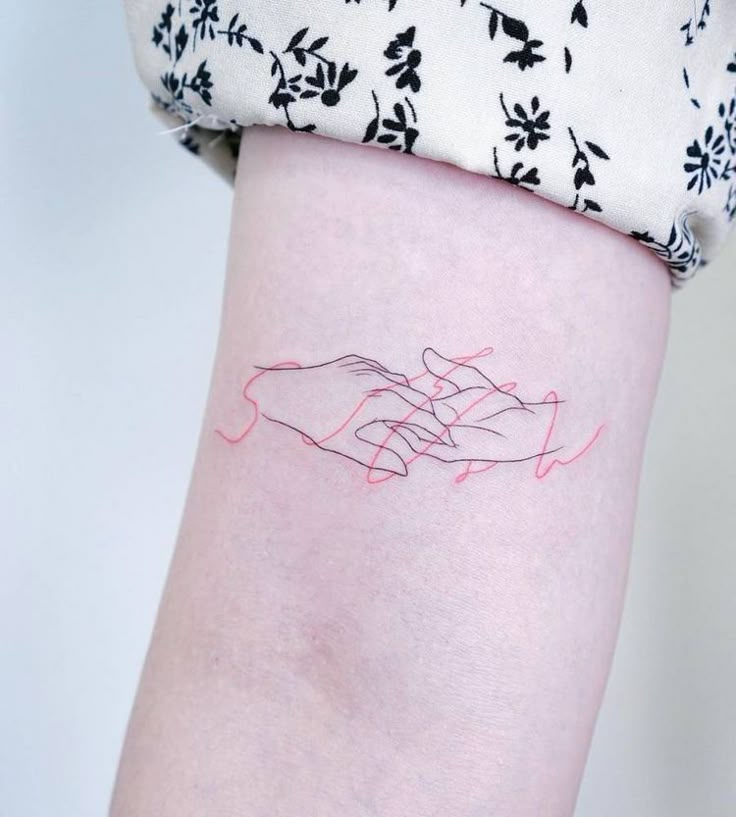 a woman's arm with a tattoo on it that has two hands holding each other