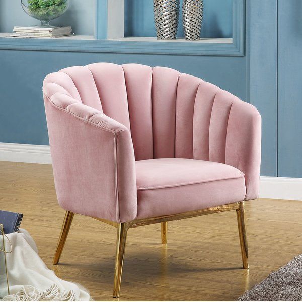 a pink chair sitting on top of a hard wood floor next to a blue wall