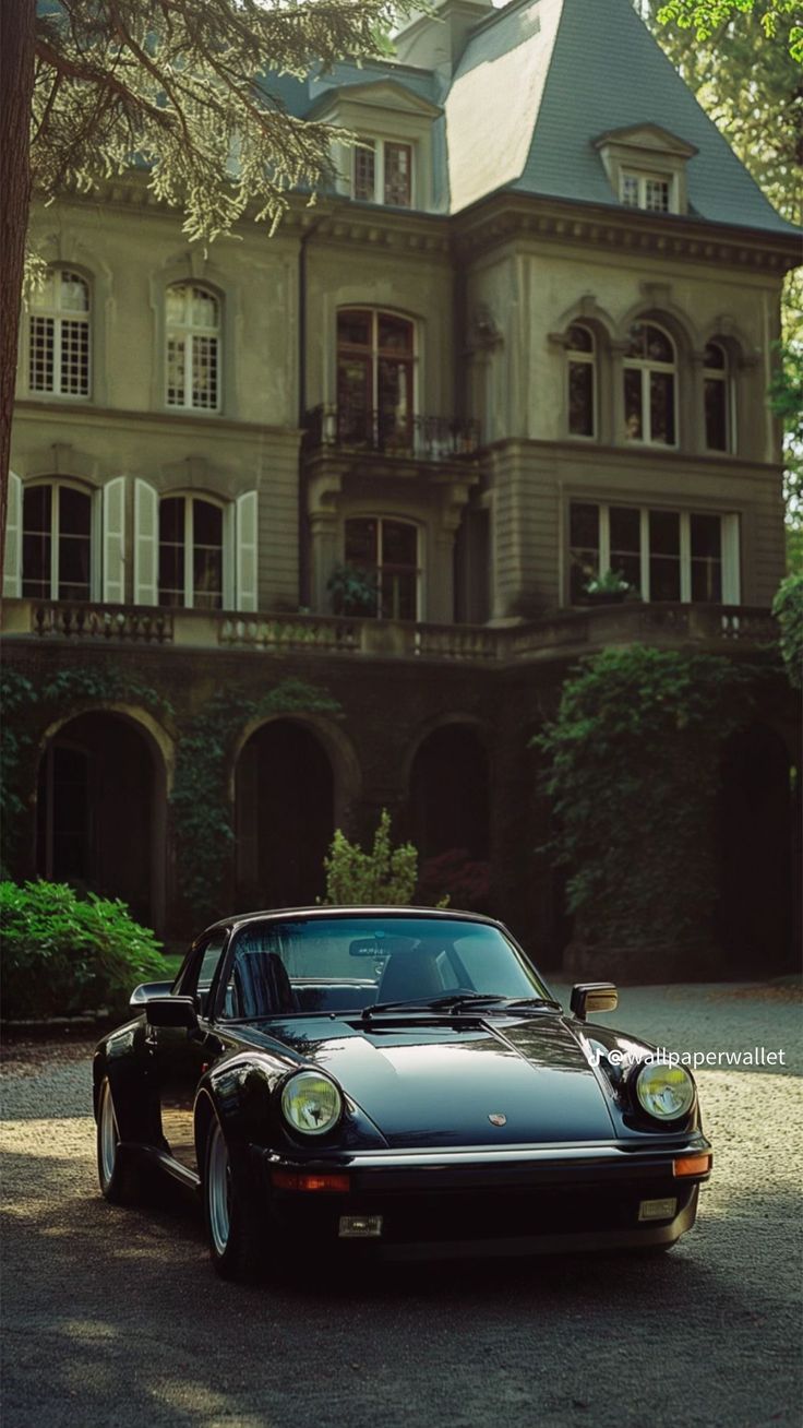 a black porsche parked in front of a large house with ivy covered walls and windows