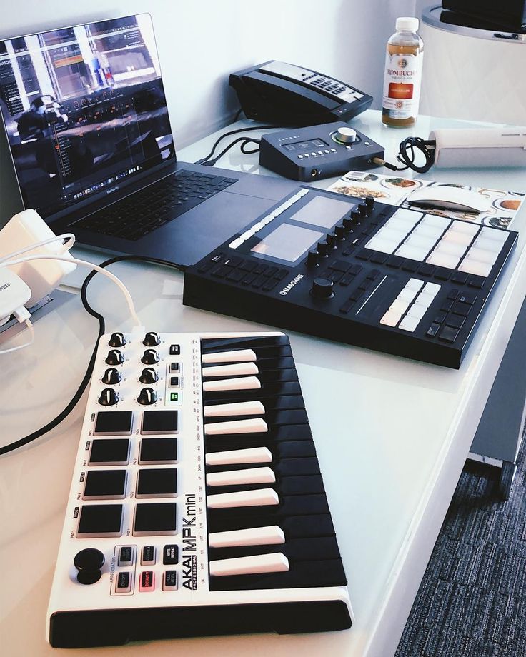 a laptop computer sitting on top of a desk next to a keyboard and sound board