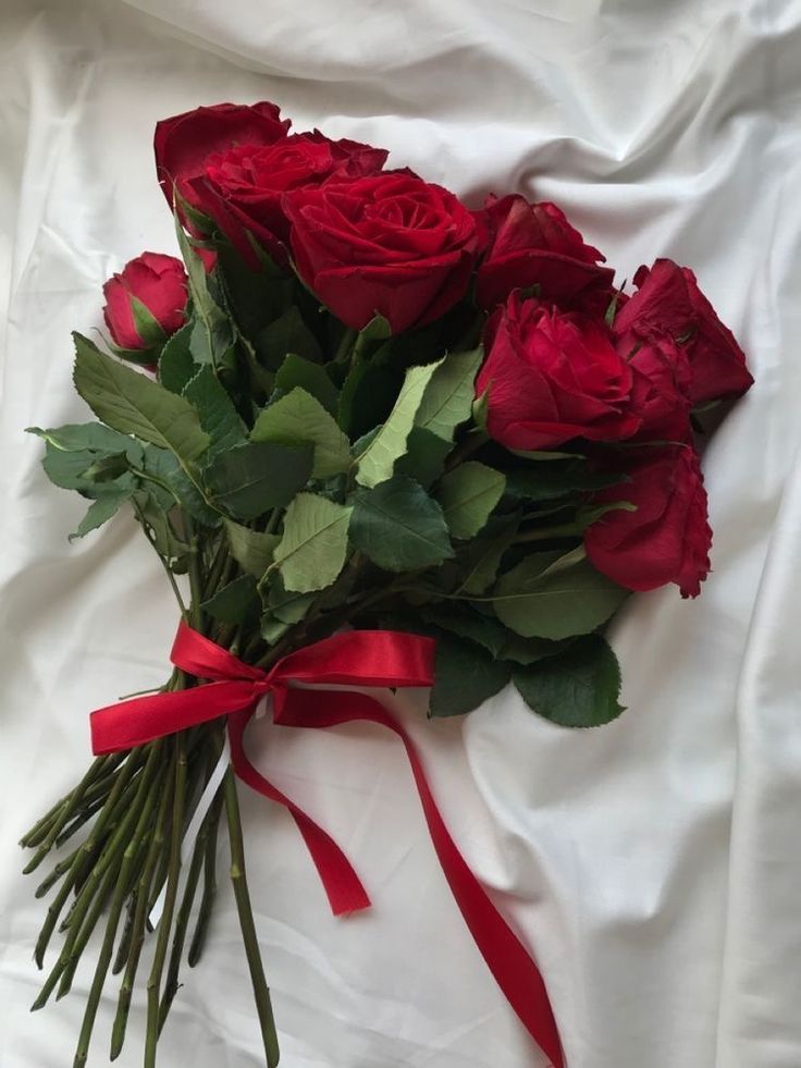 a bunch of red roses tied together on a white sheet