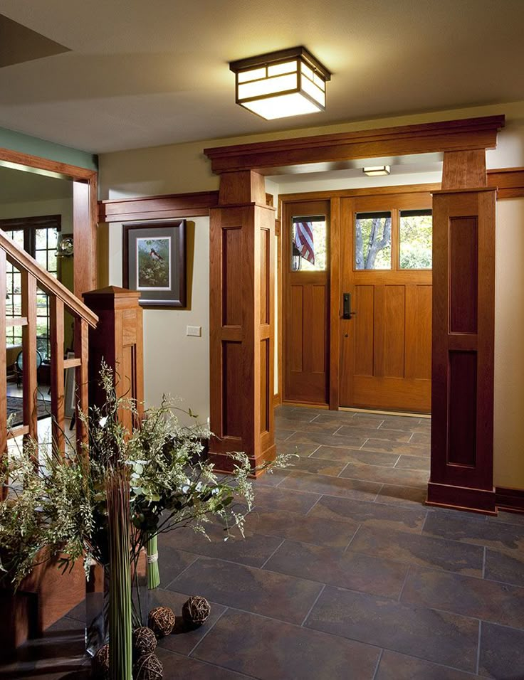 an entry way with wood paneling and glass doors on both sides, potted plants in the foreground