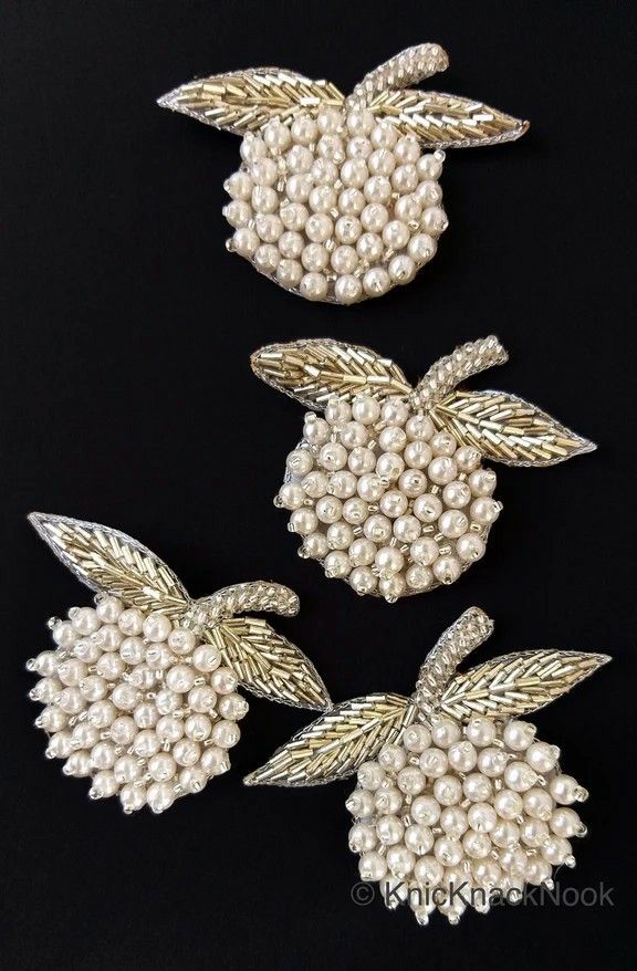 three brooches with pearls and leaves are shown on a black background in this image