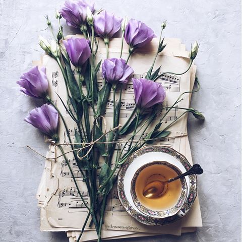 purple flowers and tea on top of an old music sheet