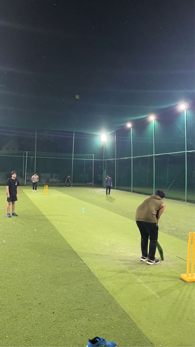 some people are playing baseball on a field at night