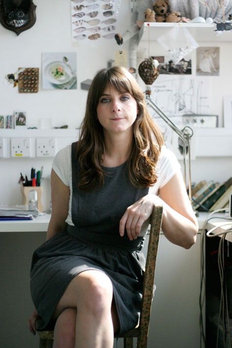 a woman sitting on a chair in front of a desk with stuffed animals hanging above her