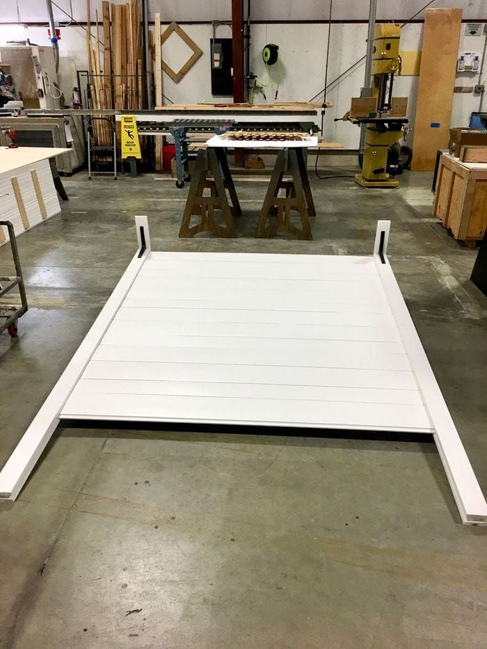 a white bed frame sitting on top of a floor in a room filled with furniture