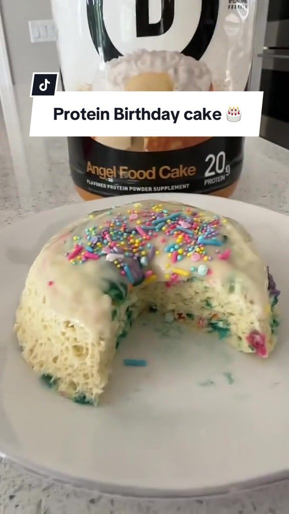 a white cake with sprinkles on it sitting on top of a plate