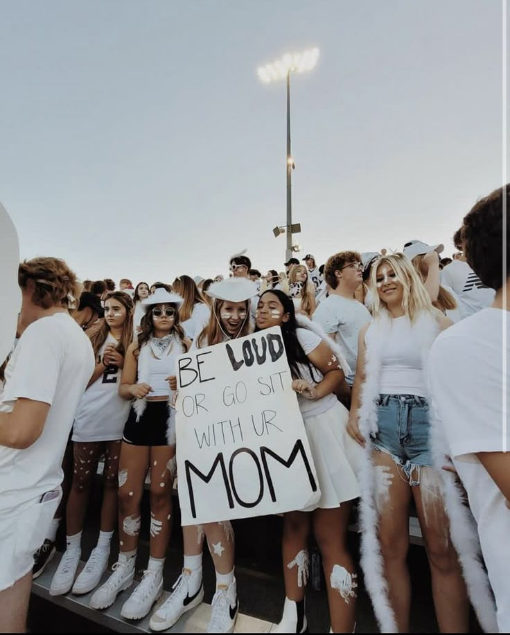 a group of people standing next to each other holding a sign that says be loud or go sit with us mom