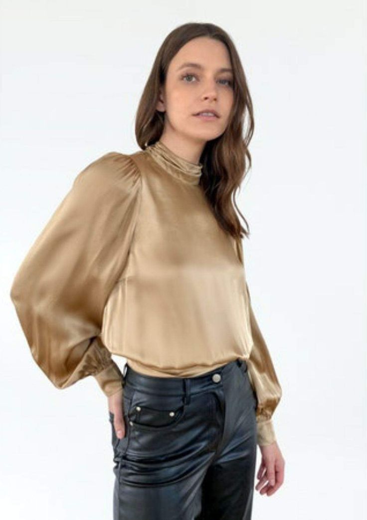 Constructed from a fine silk sandwash charmeuse, the Valencia is an elegant statement blouse set to start and finish your wardrobe in a flash. This perfectly feminine puff sleeve blouse features puff shoulders, button-up cuffs, and an open back with a self tie at the hem. The Valencia is a year-round essential and functions as a day to night outfitting staple. Finished with a self-covered button closure at the center back neck. The Valencia is unlined. Luxury Gold Raw Silk Top, Luxury Silk Top With Collared Neckline, Luxury Padded Silk Blouse, Premium Silk Feminine Tops, Luxury Silk Formal Tops, Luxury Slub Silk Blouse For Festive Occasions, Luxury Silk Tops For Daywear, Luxury Classic Gold Blouse, Luxury Art Silk Padded Top