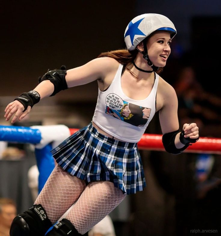 a woman in a skirt and helmet is on roller skates at an indoor event