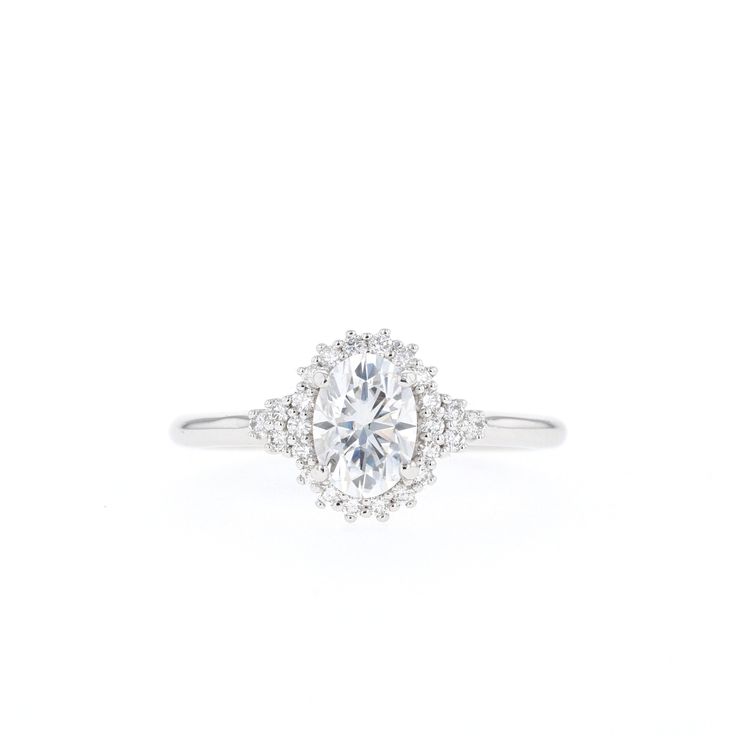 a white gold ring with an oval cut diamond surrounded by small diamonds